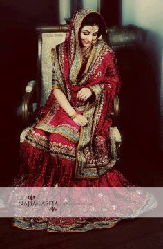 a woman sitting in a chair wearing a red and gold wedding dress with an elaborate veil