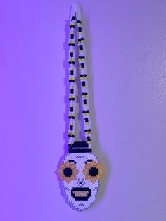 a beaded keychain hanging on a wall with an emoticive face