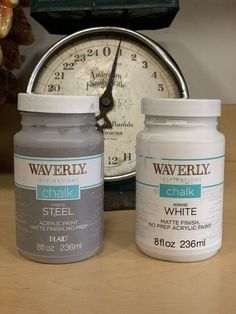 two jars of white paint next to a clock