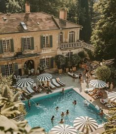 an outdoor swimming pool surrounded by umbrellas and people