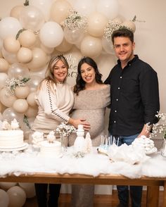 two people standing next to a table with cake and balloons