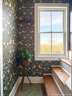 a window in a room with floral wallpaper and wooden steps leading up to it