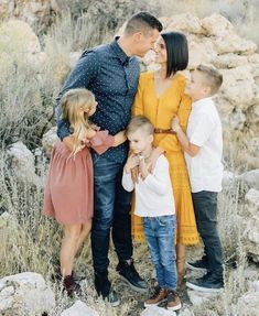 a family is posing for a photo in the desert with rocks and grass behind them