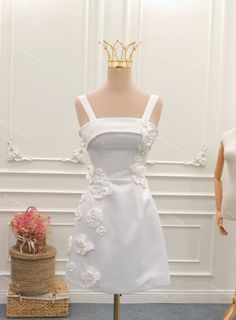 a mannequin wearing a white dress with flowers on the skirt and a gold tiara