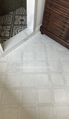 a bathroom with a white tile floor next to a wooden dresser