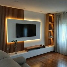 a living room with a large flat screen tv mounted on the wall and wooden flooring