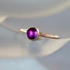 A beautiful, rich purple Amethyst gem sparkles in a bezel setting atop a lightly hammered gold band--all the metal is real 14k gold. The hammering technique I use on the band creates a faceted effect for a gorgeous play of light. The Amethyst is a smooth, rounded cabochon measuring 6mm in diameter, and the band measures 1.5mm wide. The 14k gold I use is recycled and refined in the U.S. in an environmental-award-winning plant. Amethyst is the birthstone for February and has long been prized for i Yellow Gold Amethyst Solitaire Jewelry, 14k Gold Polished Amethyst Ring, 14k Gold Amethyst Ring With Polished Finish, 14k Gold Round Amethyst Ring With Polished Finish, Gold Amethyst Ring With Bezel Setting, Gift Yellow Gold Amethyst Ring With Bezel Setting, Purple 14k Gold Amethyst Bezel Setting Ring, Yellow Gold Amethyst Ring With Bezel Setting Gift, Amethyst Birthstone Ring In Yellow Gold