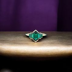 an emerald colored ring sitting on top of a wooden table