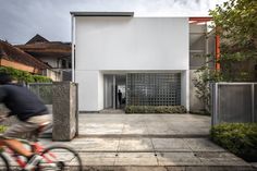 a man riding a bike past a tall white building