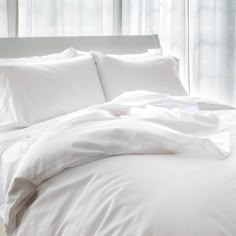 an unmade bed with white sheets and pillows