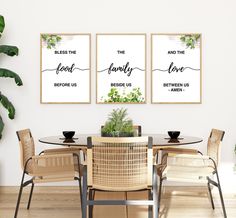 a dining room table with four chairs and two posters on the wall above it that says,