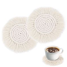 two white coasters and a cup of coffee on a white background with a spiral design in the middle