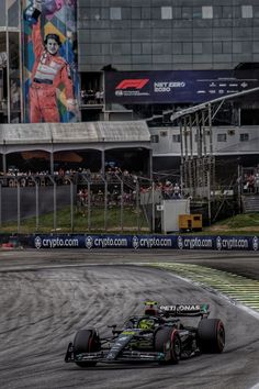 a man driving a race car around a track in front of a large group of people