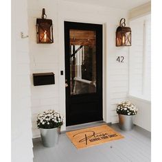 the front door is decorated with flowers and potted plants, along with an address mat