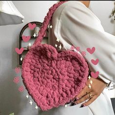 a woman holding a pink crocheted heart purse