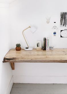 a wooden table topped with books next to a lamp and pictures on the wall behind it