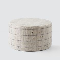 a round ottoman made out of woven material with black and white lines on the top