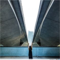 a woman is standing in the middle of an underpass with her hands up to the sky