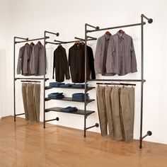 an open closet with clothes and shoes hanging on the wall next to a wooden floor