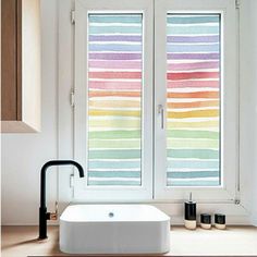 a bathroom with a tub and window covered in multicolored blinds