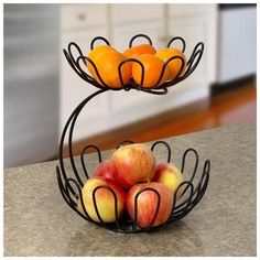 two tiered metal fruit stand with apples and oranges in it on a kitchen counter