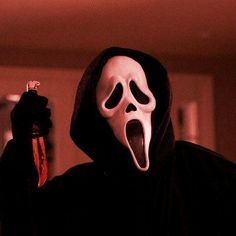 a person wearing a ghost mask holding a lighter