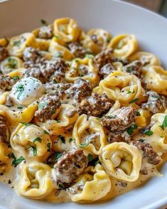 a white plate topped with pasta covered in cheese and meat sauce, garnished with parsley