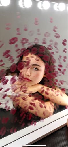 a woman's reflection in a mirror with her hands on her chest and red spots all over her body