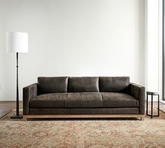 a couch sitting on top of a wooden floor next to a lamp