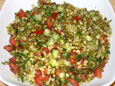 a white plate topped with cucumber and tomato salad on top of a wooden table