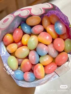 a bag filled with lots of candy sitting on top of a white counter next to a person's hand