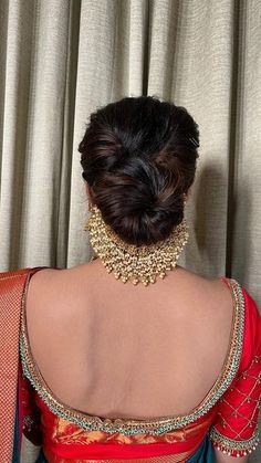 the back of a woman's head wearing a red and blue sari with gold jewelry