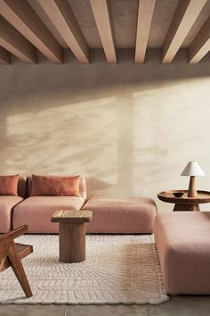 a living room with pink couches and wooden tables in the corner, along with a white rug on the floor