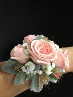 a wrist corsage with pink roses and white flowers