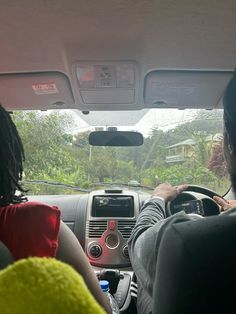 two people sitting in the driver's seat of a car, looking out the window