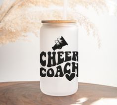 a white mason jar with the words cheer coach on it sitting on a wooden table