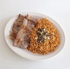 a white plate topped with noodles and meat next to other foods on top of it