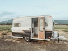 an rv parked in the middle of a field with its door open and it's interior opened