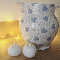 a white vase sitting on top of a wooden table next to two small pumpkins