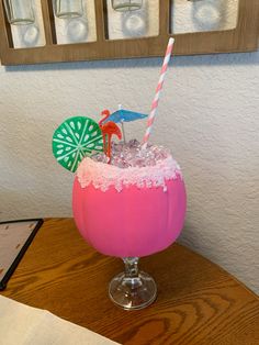 a pink drink sitting on top of a wooden table next to a framed picture and paper straws