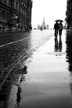 two people walking down the street with umbrellas in their hands on a rainy day