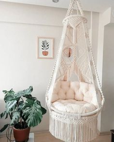 a hammock chair hanging from the ceiling in a room with potted plants