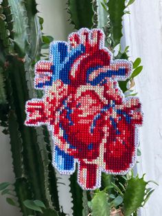 a cross stitch heart hanging on a cactus