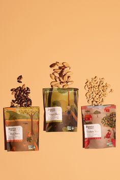 three bags of seeds are shown on a beige and orange background, one is filled with nuts