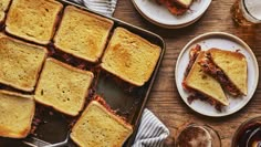 toasted sandwiches sitting on top of a pan next to beer glasses and sauces