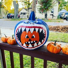 two pumpkins sitting on top of a wooden rail next to some other pumpkins