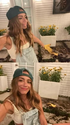 two women in overalls and hats standing next to each other