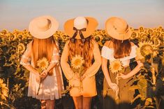 three girls in sunflower field with hats on their heads and one girl holding flowers