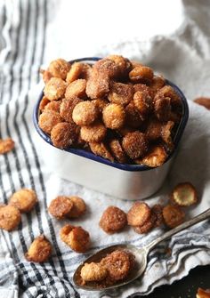 a bowl filled with fried food on top of a table next to a spoon and napkin