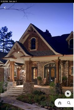 a house with stone and wood trimmings in the front yard at night time